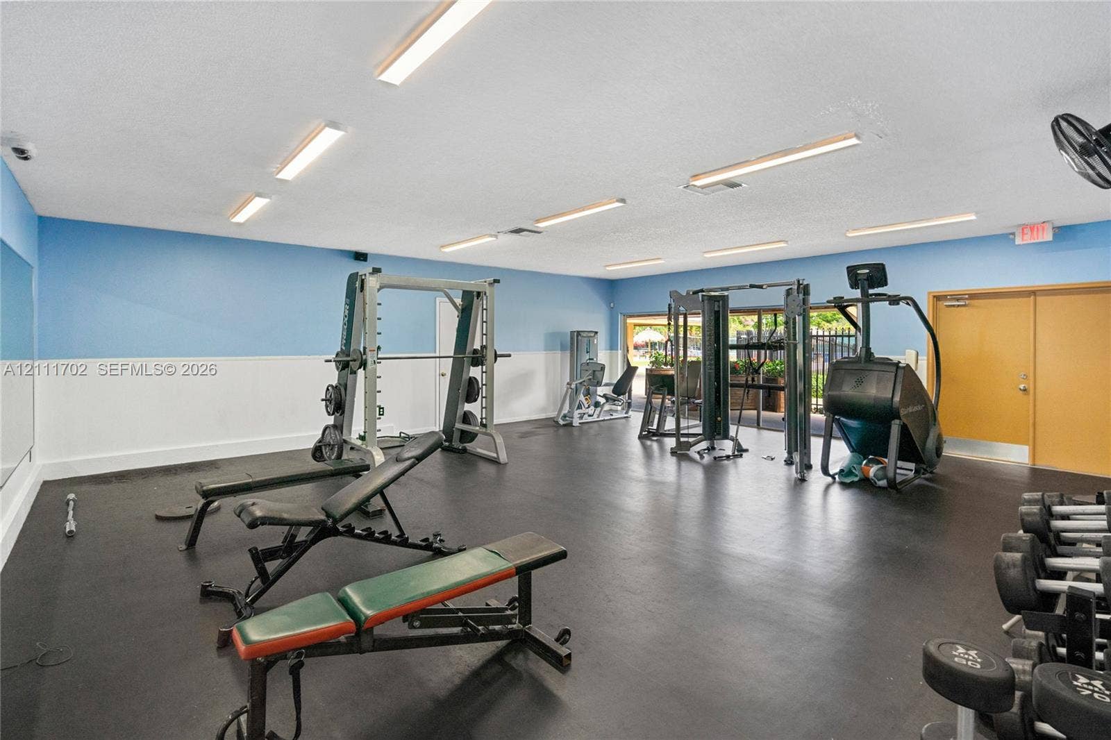 Fitness room featuring rubberized flooring, high-output linear lighting, and dual-tone wall finishes