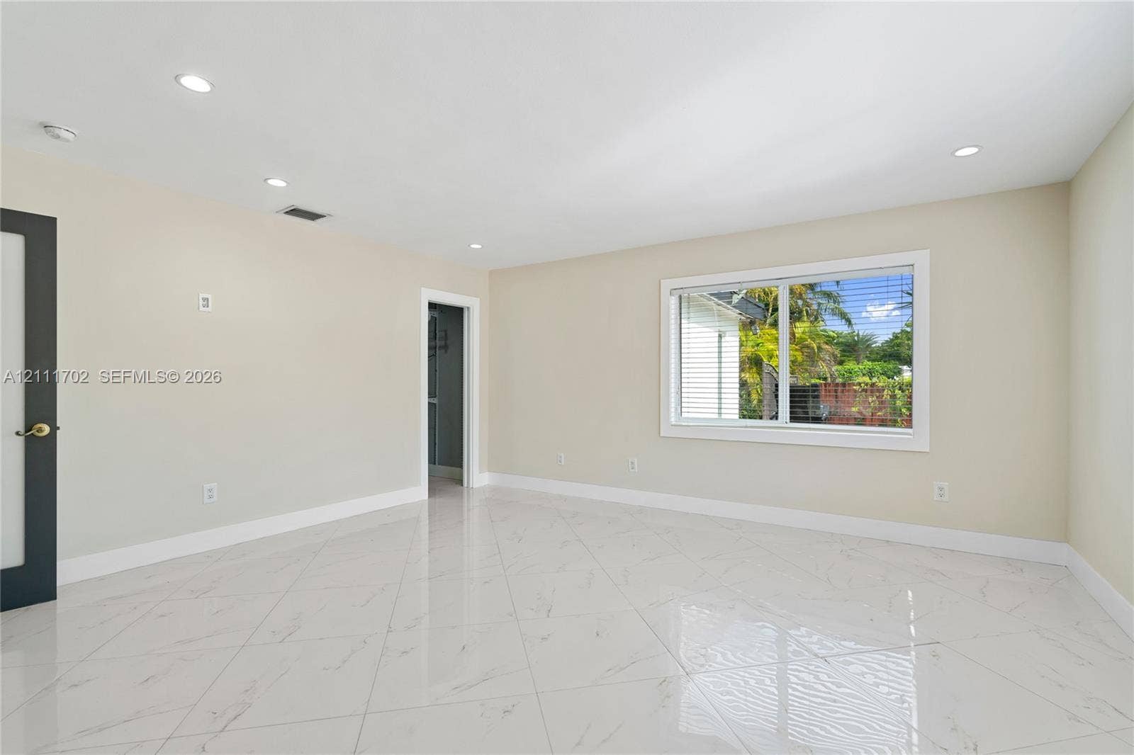 Light-filled room featuring large-format tile flooring with marble-finish veining, crisp neutral wall paint, recessed lighting, and a single-pane horizontal window