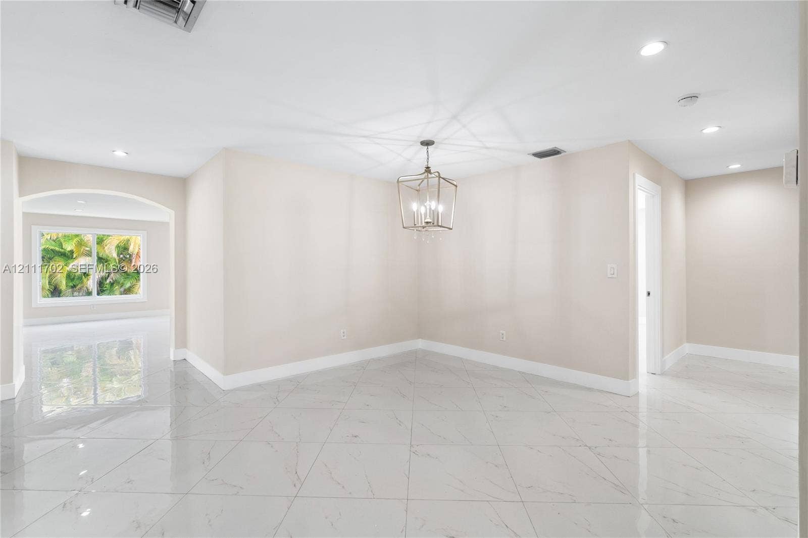 Polished porcelain tile flooring, recessed lighting, arched architectural detail, and a modern geometric pendant light fixture