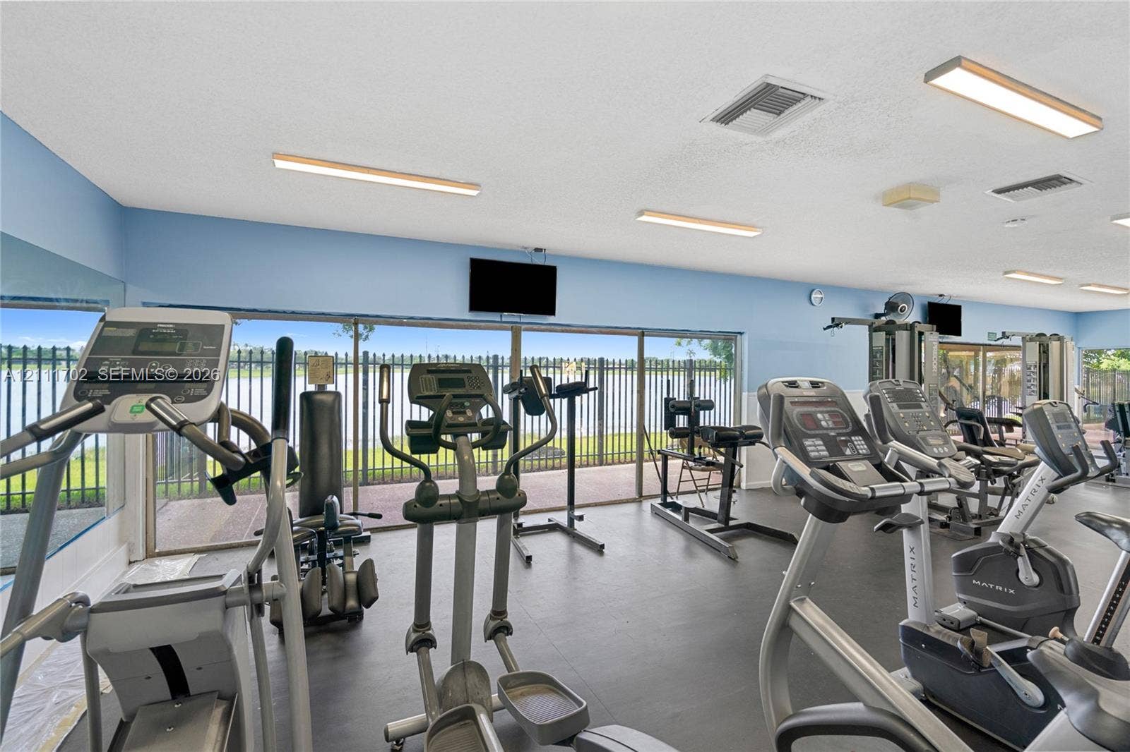 Fitness center featuring floor-to-ceiling windows, full-length wall mirrors, and hard-surface flooring