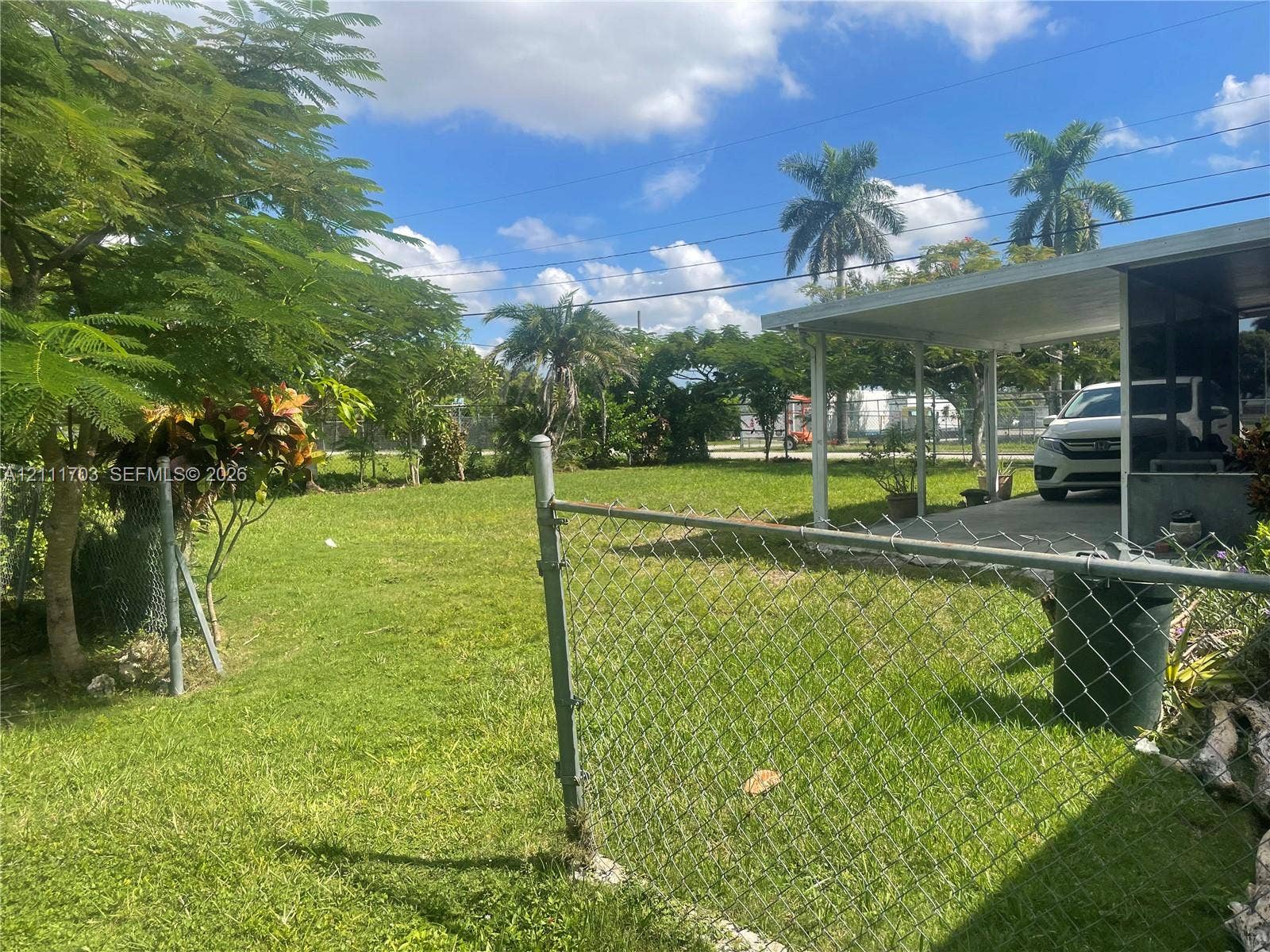 21840 SW 118th Avenue, Miami, FL 33170 Expansive backyard featuring a chain-link fence, concrete patio covering, and mature trees