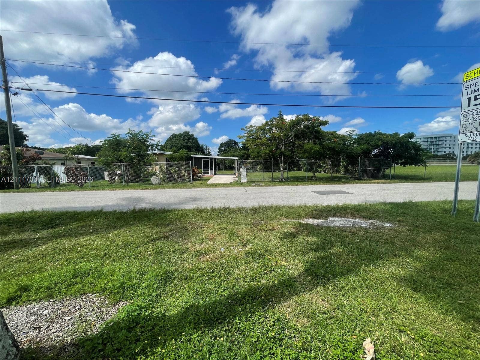 21840 SW 118th Avenue, Miami, FL 33170 Single-story residence featuring a paved entryway, chain-link perimeter fencing, and mature trees