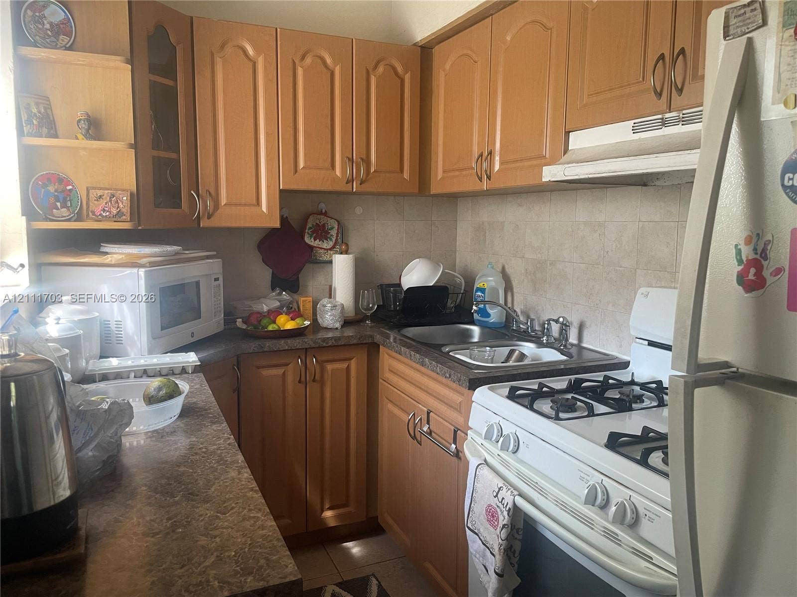 21840 SW 118th Avenue, Miami, FL 33170 Kitchen featuring wood-finish cabinetry, a dual-basin stainless steel sink, a tile backsplash, and stone-finish laminate countertops