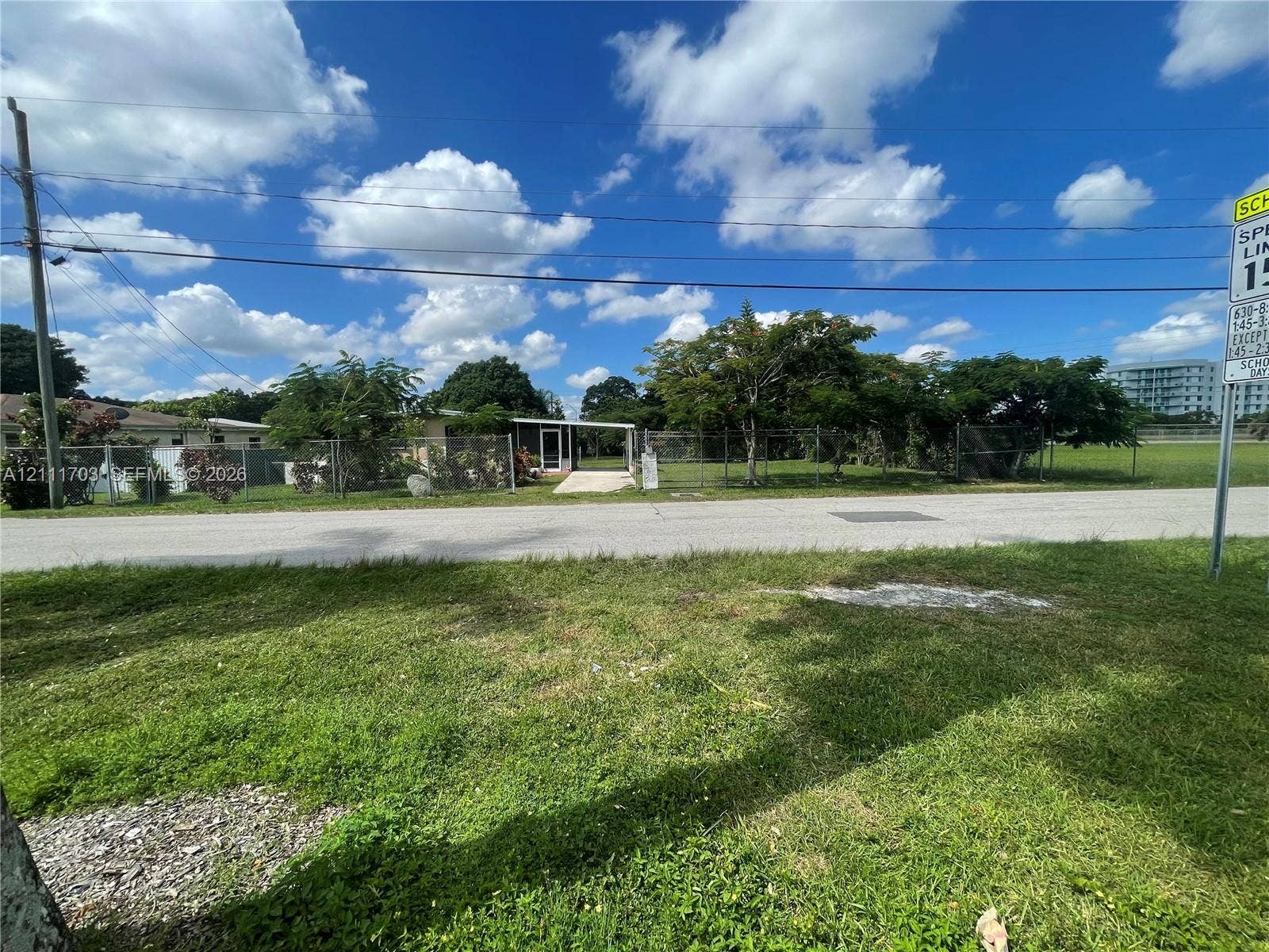 21840 SW 118th Avenue, Miami, FL 33170 Single-story residence featuring a covered entryway, paved driveway, and chain-link fencing enclosing the property grounds