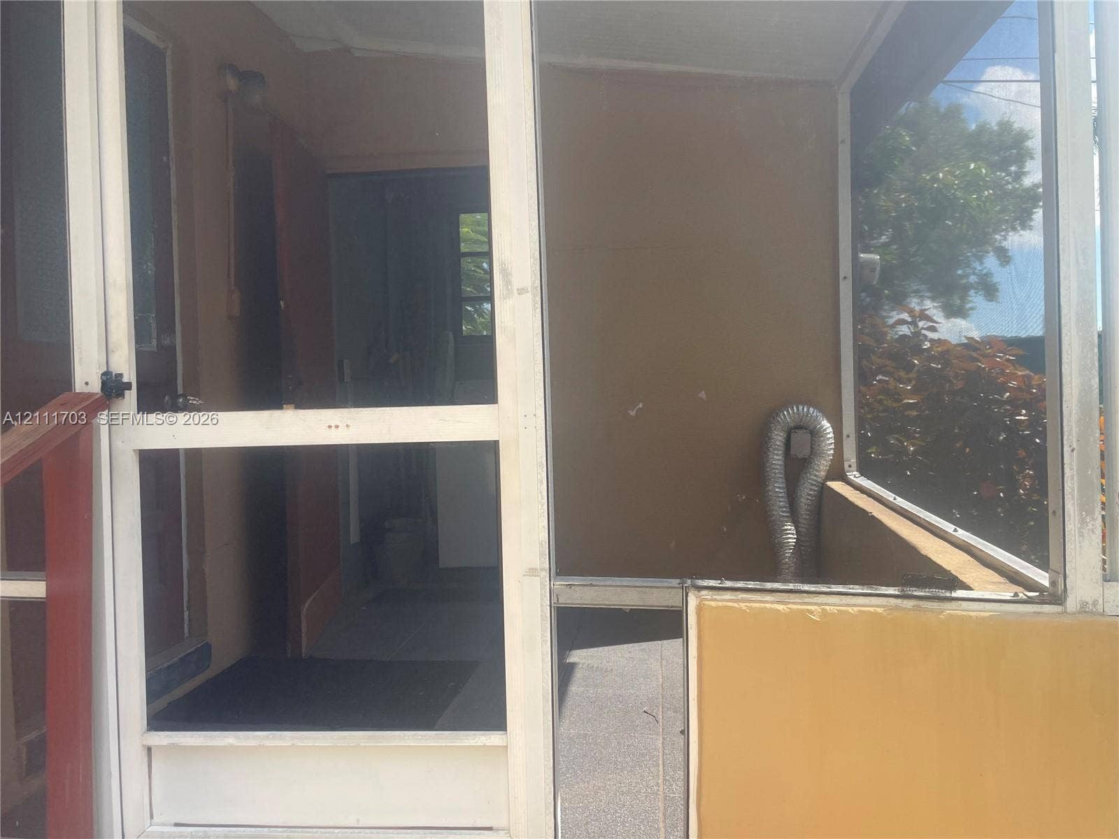 21840 SW 118th Avenue, Miami, FL 33170 Screened porch featuring metal framing, solid lower wall panels, concrete flooring, and an integrated hinged screen door