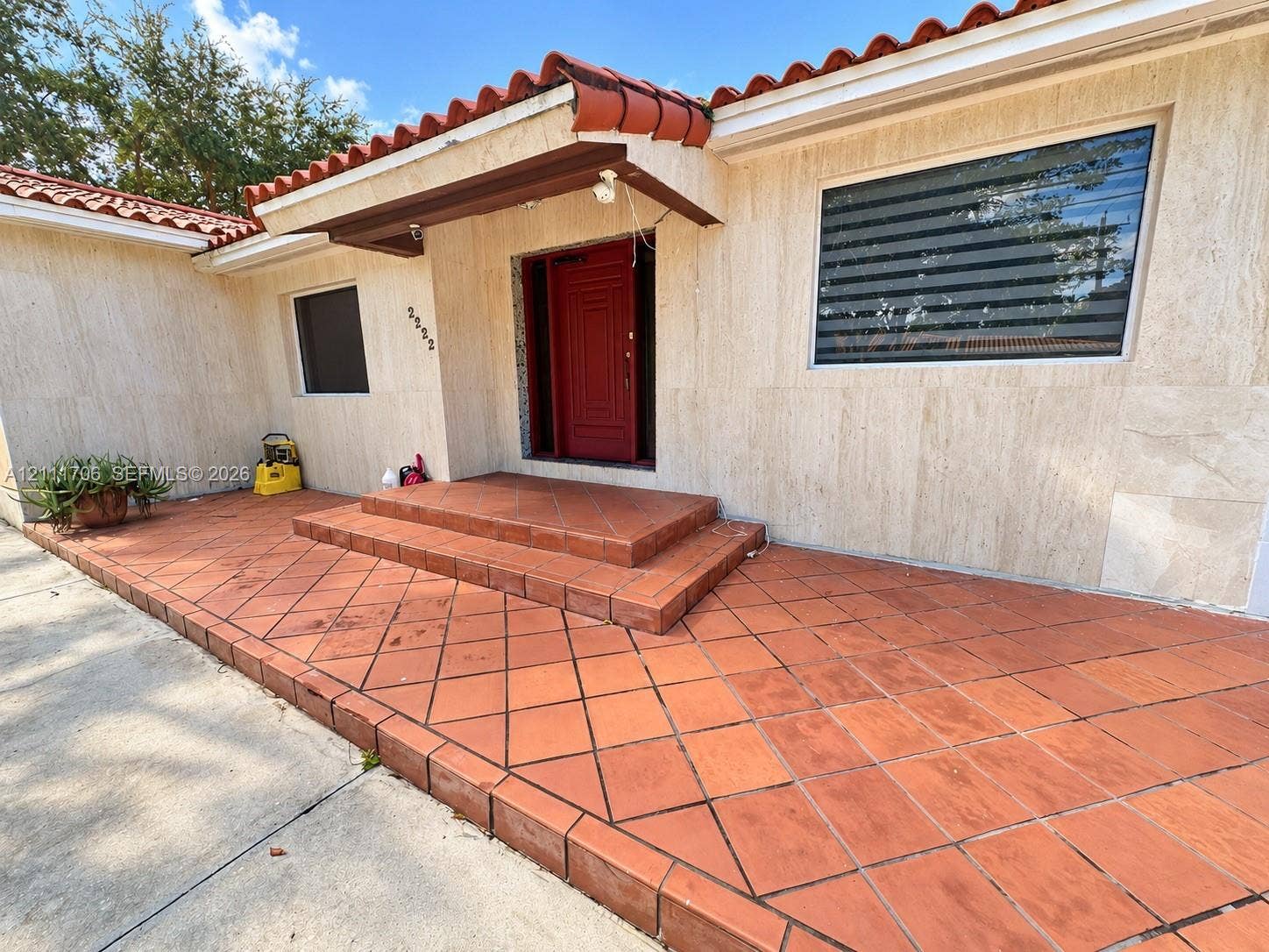 2222 SW 19th Avenue, Miami, Miami, FL 33145 Exterior entrance featuring natural stone wall cladding, a terracotta tile porch, a low-profile overhang with a barrel-tile roof, and a solid-core entry door