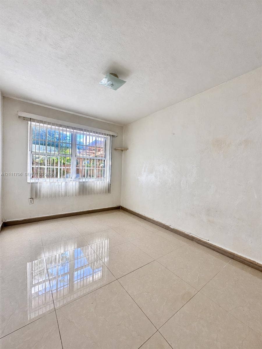 2222 SW 19th Avenue, Miami, Miami, FL 33145 Interior space featuring large-format ceramic tile flooring, a multi-pane window with security bars, and a flush-mount ceiling light fixture