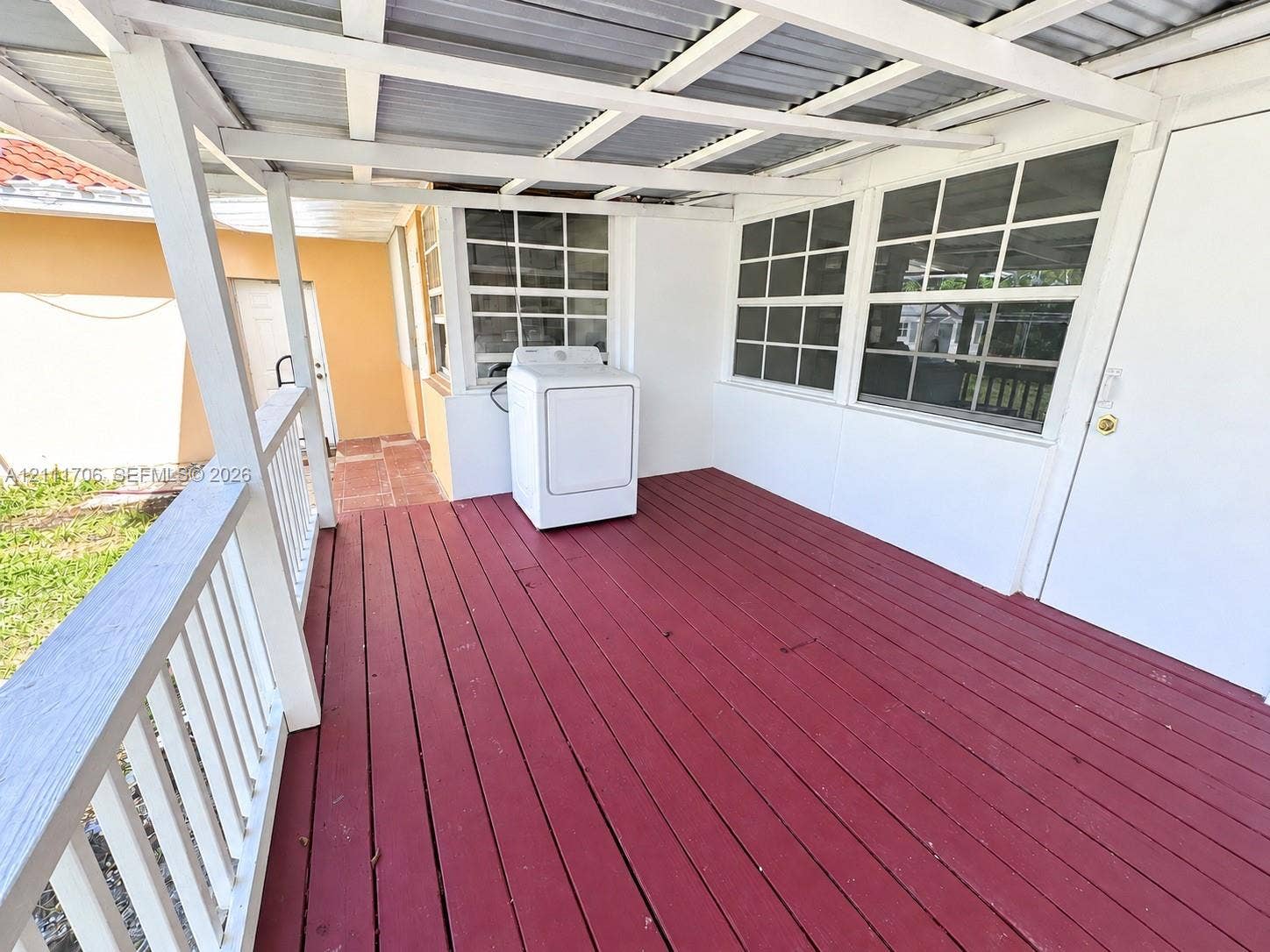 2222 SW 19th Avenue, Miami, Miami, FL 33145 Covered porch featuring wood decking, white balustrades, a metal roof structure, and multi-pane windows