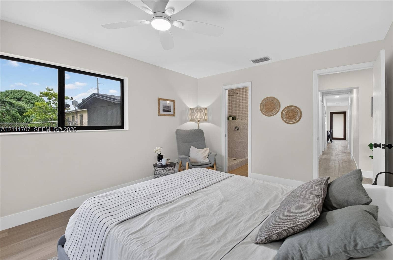 301 SW 12th Avenue, Delray Beach, FL 33444 Neutral-toned interior featuring wood-finish flooring, a contemporary ceiling fan with integrated lighting, and large, black-framed picture windows