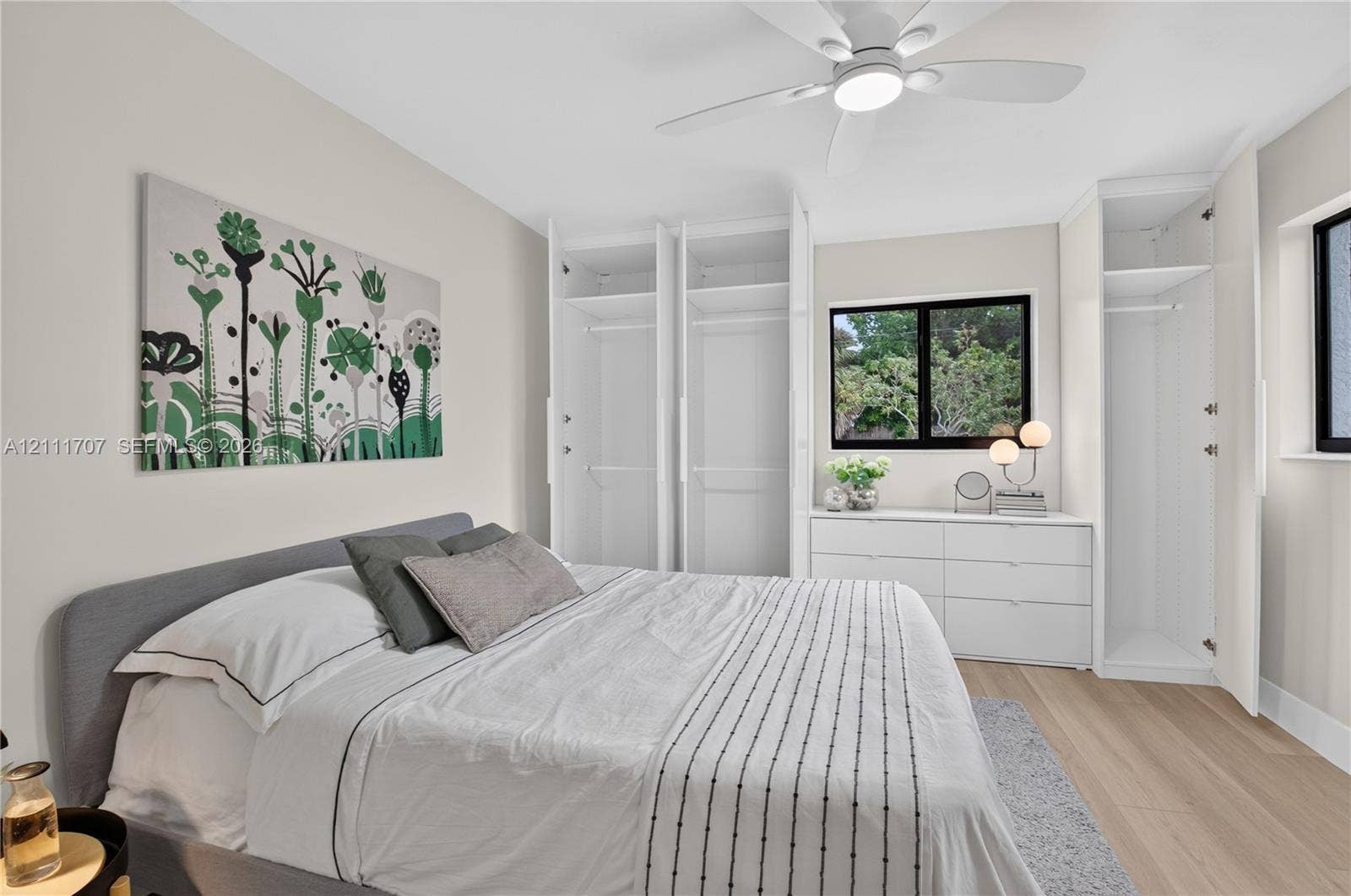 301 SW 12th Avenue, Delray Beach, FL 33444 Built-in floor-to-ceiling closet cabinetry, light-toned wood-finish flooring, dual-pane windows with dark frames, and a modern ceiling fan with integrated lighting