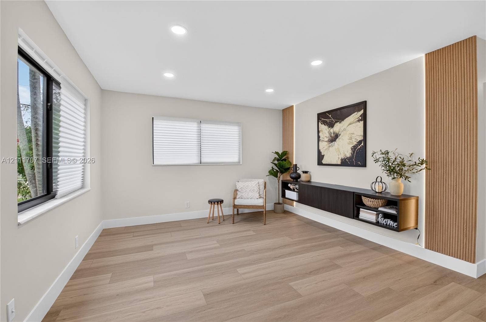 301 SW 12th Avenue, Delray Beach, FL 33444 Living area featuring light wood-finish flooring, recessed lighting, horizontal slider windows, a wall-mounted floating cabinet, and vertical wood-slat accent panels with integrated lighting