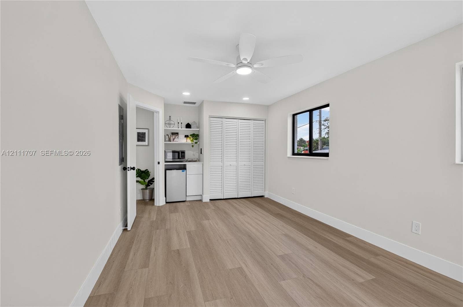 301 SW 12th Avenue, Delray Beach, FL 33444 Interior space featuring wood-finish flooring, a ceiling fan with integrated lighting, recessed lighting, white louvered closet doors, and a built-in bar with cabinetry and open shelving