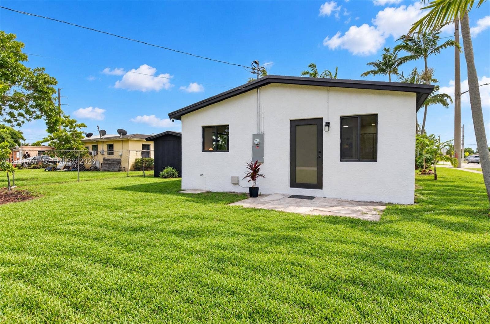 301 SW 12th Avenue, Delray Beach, FL 33444 Stucco exterior featuring a stone patio, metal-framed windows, and a dark-finish door