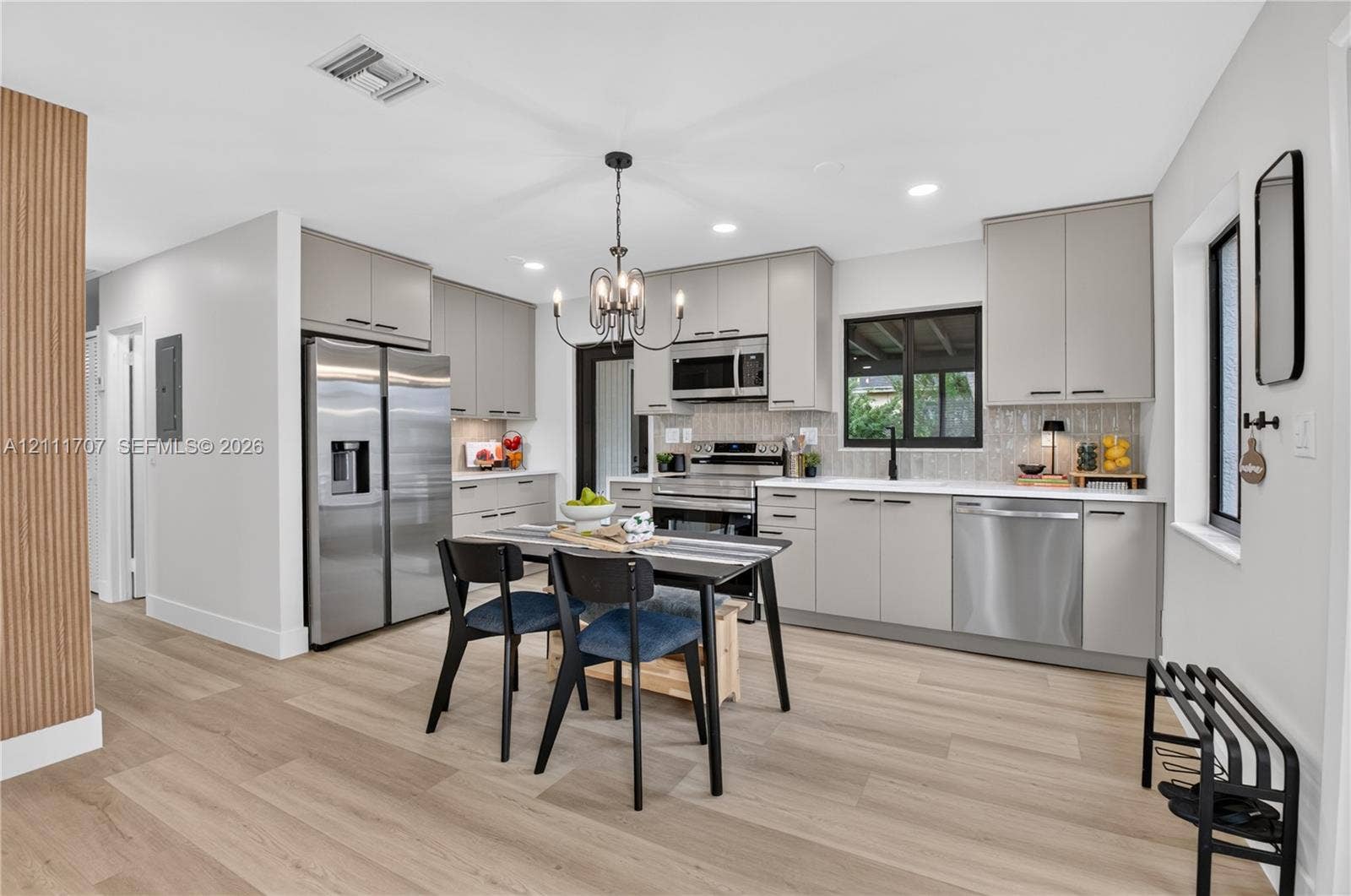 301 SW 12th Avenue, Delray Beach, FL 33444 Kitchen featuring flat-panel cabinetry, stainless steel appliances, wood-finish flooring, recessed lighting, and a chandelier fixture