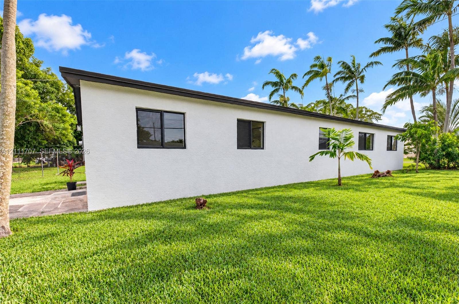 301 SW 12th Avenue, Delray Beach, FL 33444 Exterior profile featuring white stucco siding, a flat roofline, dark-framed windows, and expansive green lawn