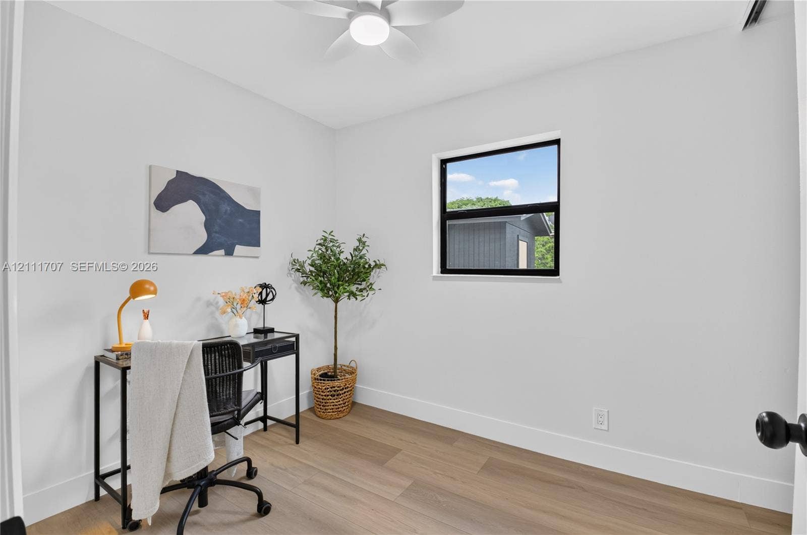 301 SW 12th Avenue, Delray Beach, FL 33444 Room featuring wood-finish flooring, a matte black window frame, and a white ceiling fan with integrated lighting
