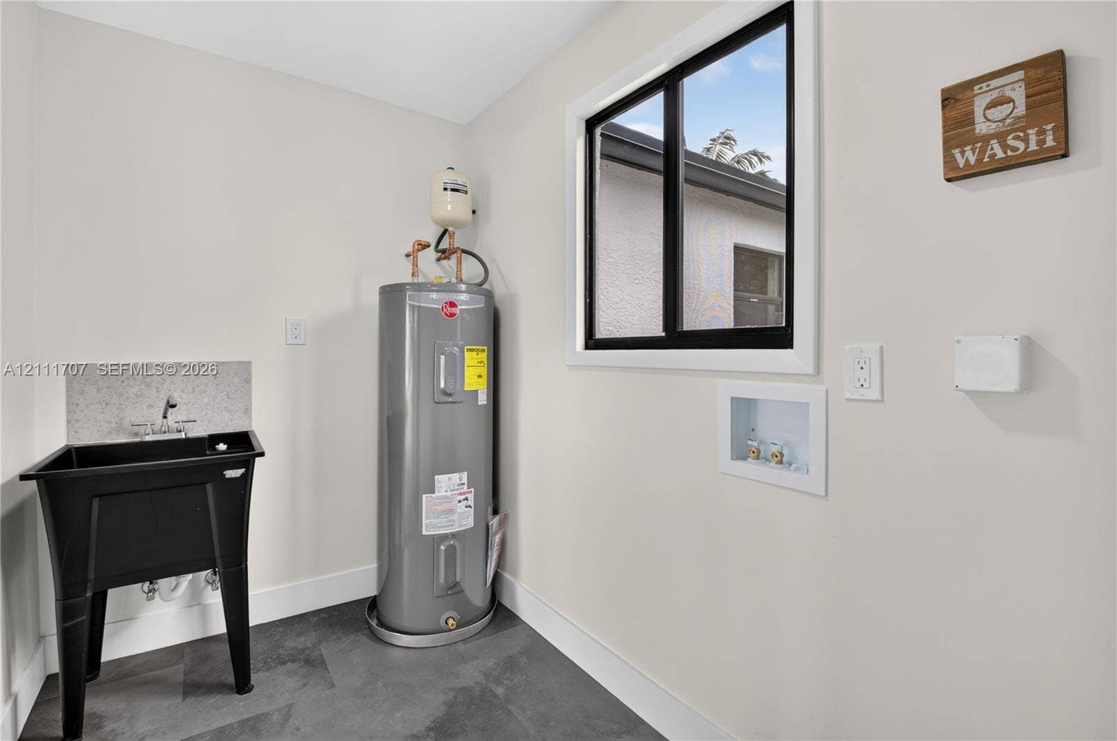 301 SW 12th Avenue, Delray Beach, FL 33444 Utility area featuring slate-style flooring, a deep basin utility sink with a stone-finish backsplash, and a dedicated water heater