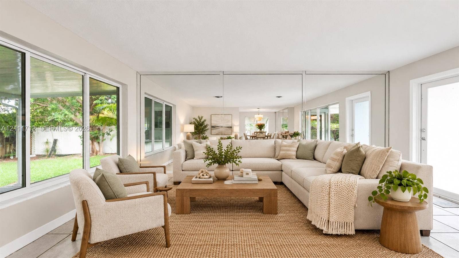 Virtually staged. Living space featuring expansive floor-to-ceiling windows, large-format tile flooring, and a mirrored wall accent