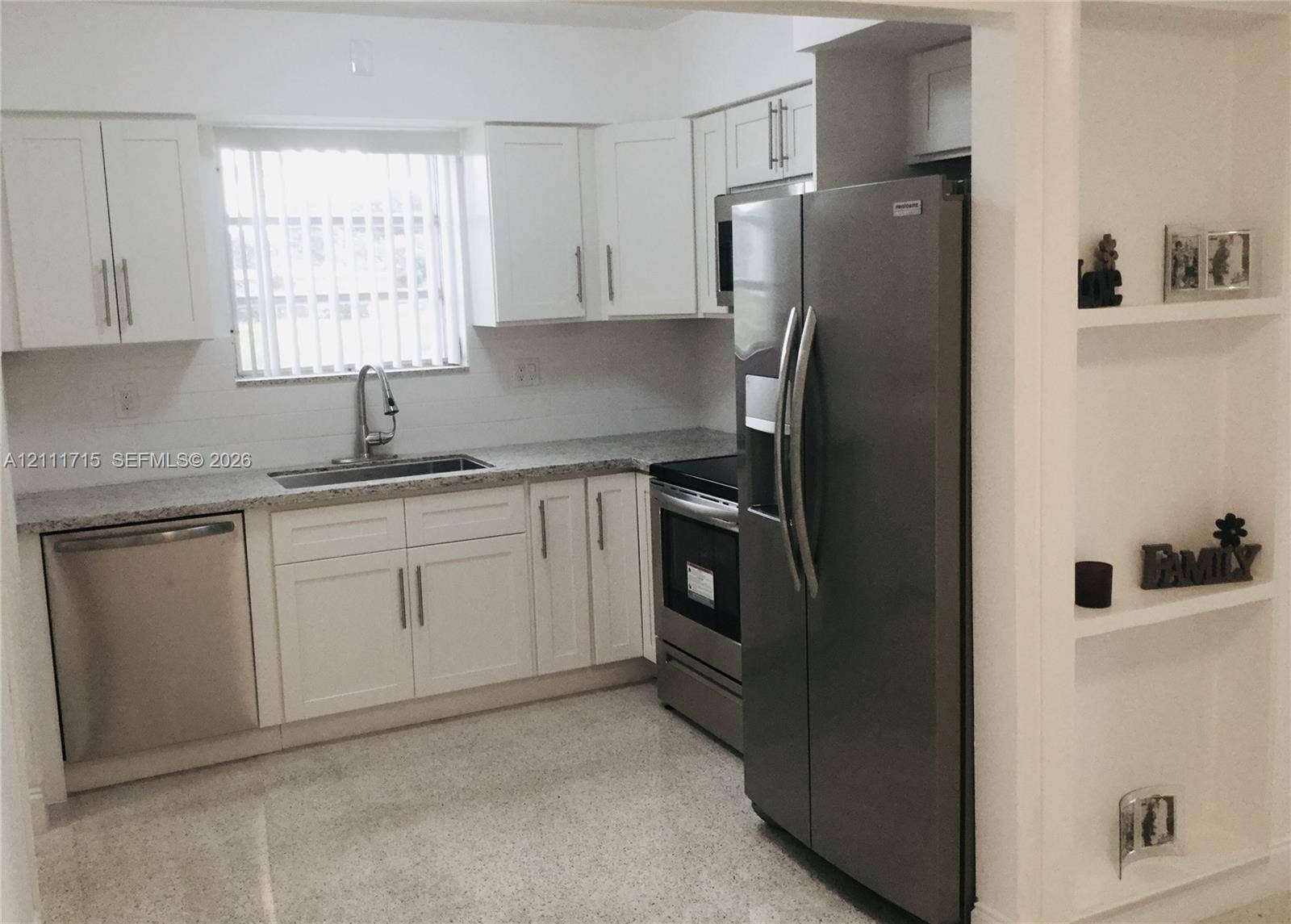 18280 NE Glades Drive, North Miami Beach, North Miami Beach, FL 33162 Kitchen featuring white shaker-style cabinetry, stainless steel appliances, speckled stone-finish countertops, an undermount sink with a gooseneck faucet, and built-in wall shelving