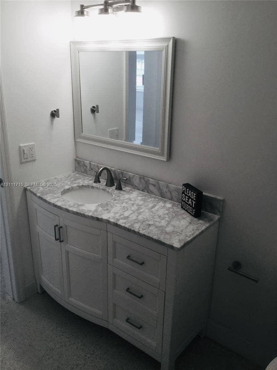 18280 NE Glades Drive, North Miami Beach, North Miami Beach, FL 33162 White shaker-style vanity with stone-patterned countertop, integrated basin, brushed metal hardware, and framed wall mirror