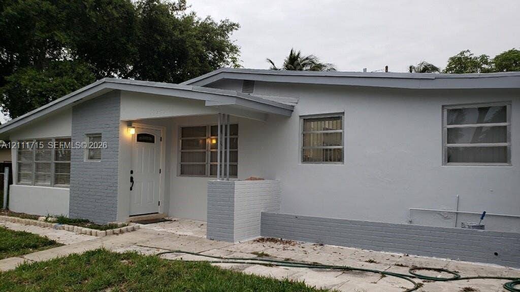 18280 NE Glades Drive, North Miami Beach, North Miami Beach, FL 33162 Single-story exterior featuring painted brick accents, horizontal sliding windows, a recessed entryway, and a covered porch