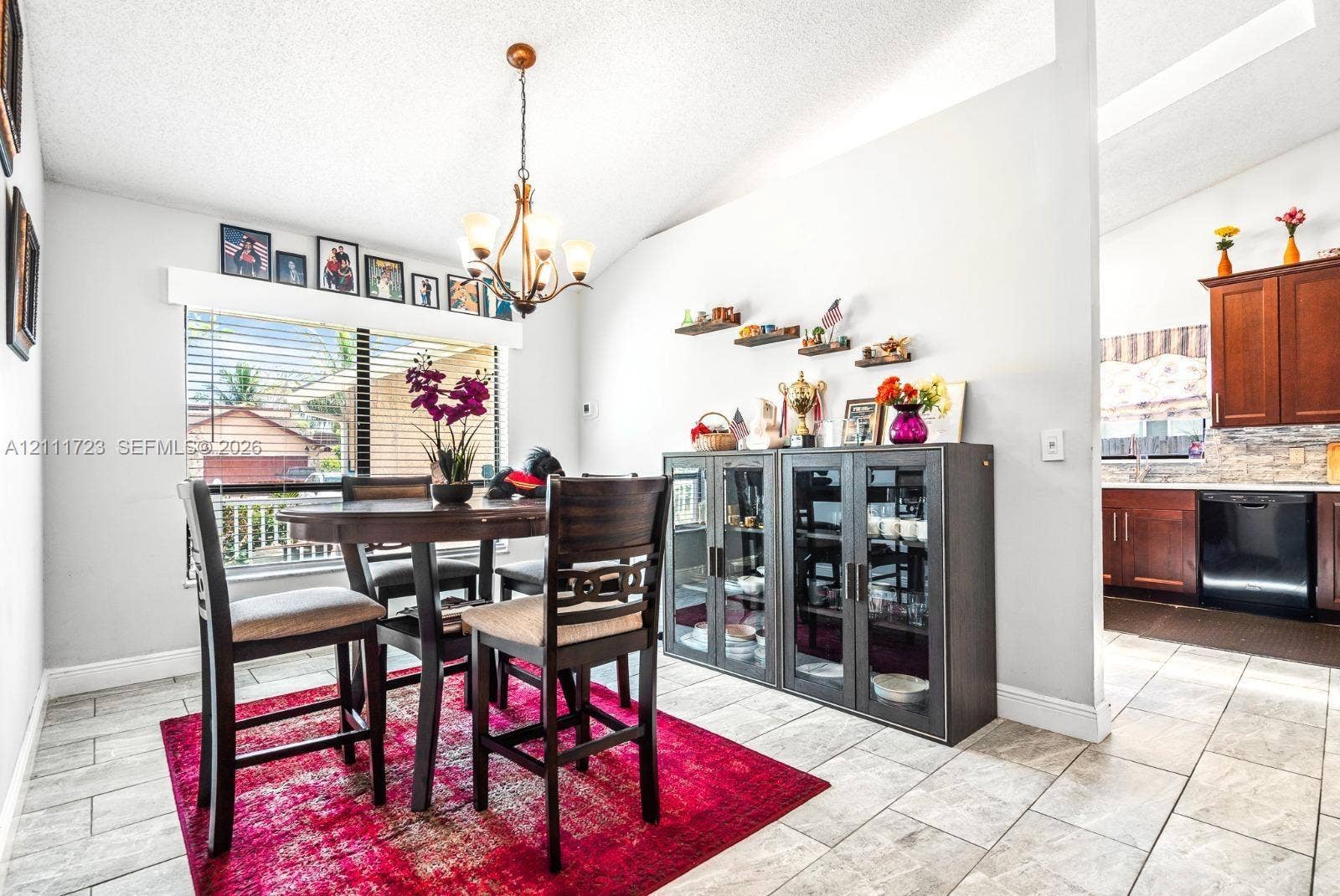 8541 NW 51st Court, Lauderhill, FL 33351 Dining area featuring a vaulted ceiling, multi-light chandelier, and ceramic tile flooring