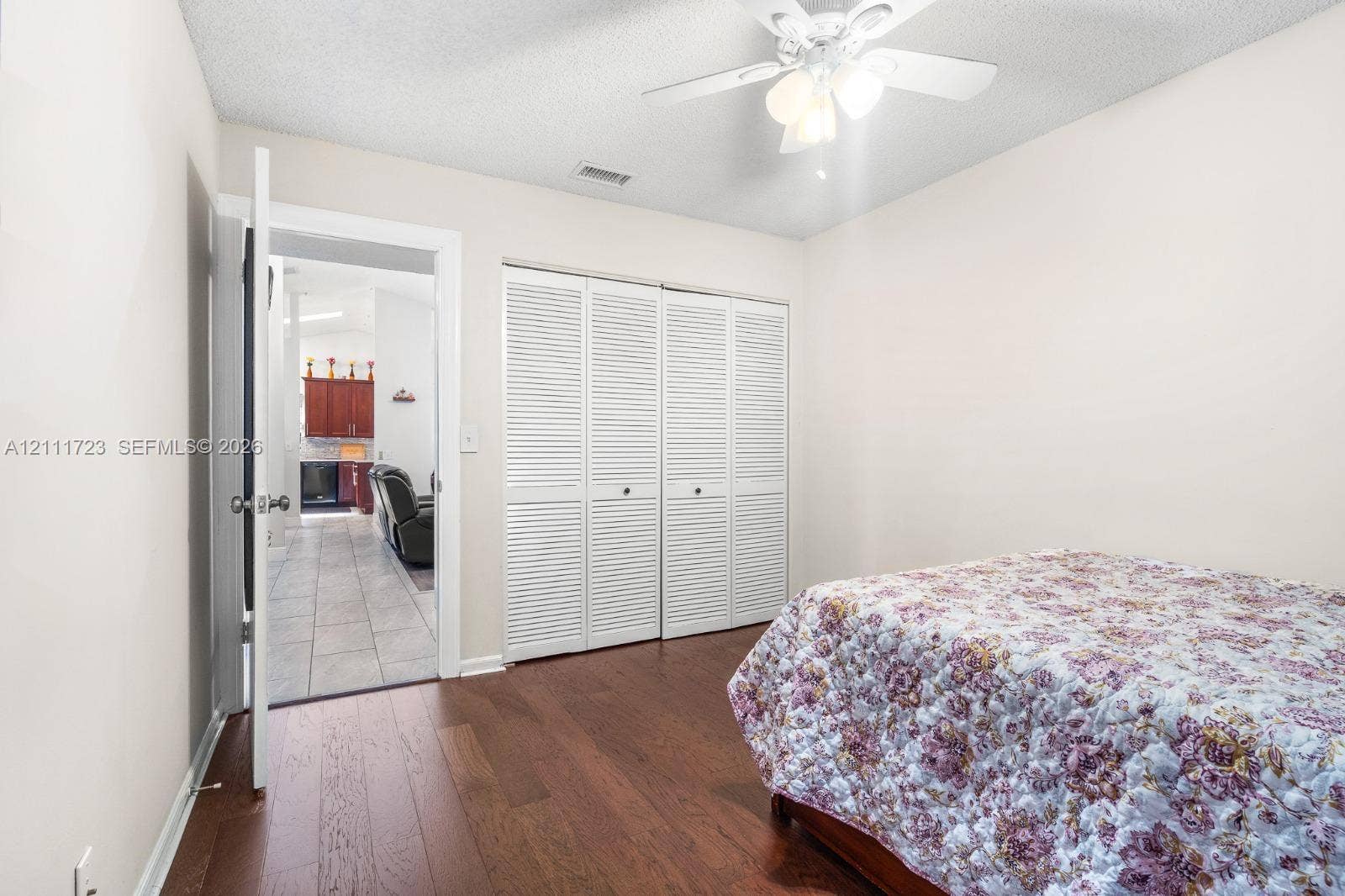 8541 NW 51st Court, Lauderhill, FL 33351 Interior room featuring wood-finish flooring, a ceiling fan with integrated light fixture, and double louvered closet doors