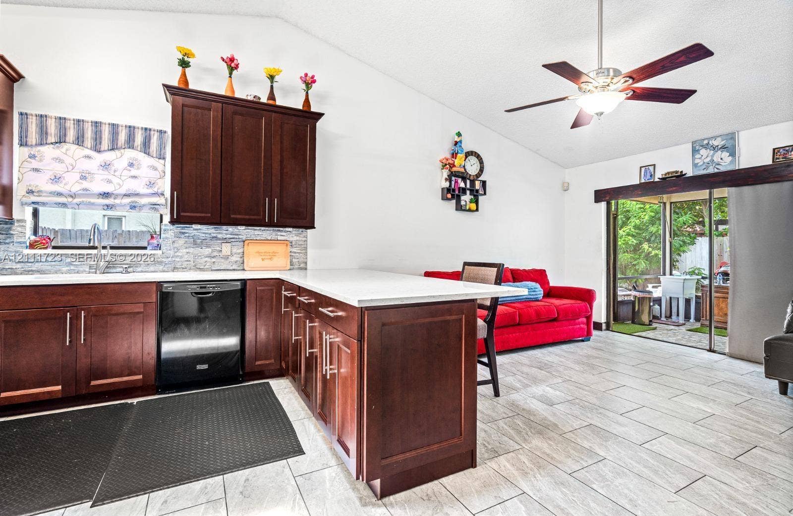 8541 NW 51st Court, Lauderhill, FL 33351 Kitchen featuring dark wood cabinetry, light-toned stone-finish countertops, tile backsplash, tile flooring, and a ceiling fan