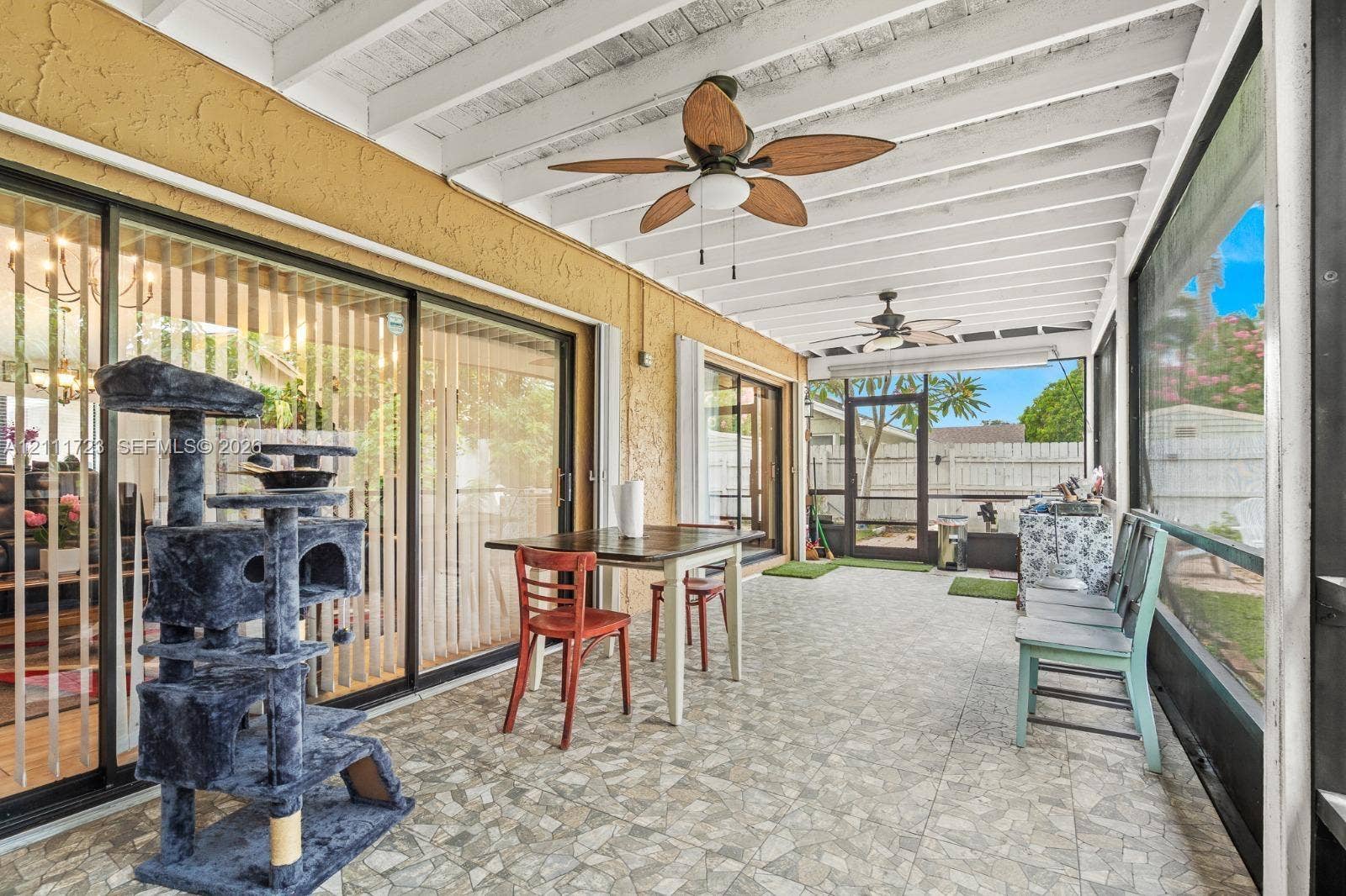 8541 NW 51st Court, Lauderhill, FL 33351 Screened-in patio featuring a textured concrete floor, white exposed-beam ceiling, and dual ceiling fans