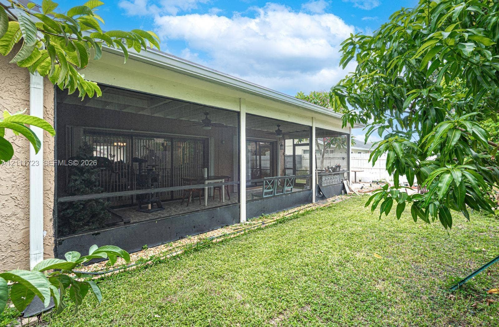 8541 NW 51st Court, Lauderhill, FL 33351 Screen-enclosed patio featuring a solid roof, integrated ceiling fans, and sliding glass door entry