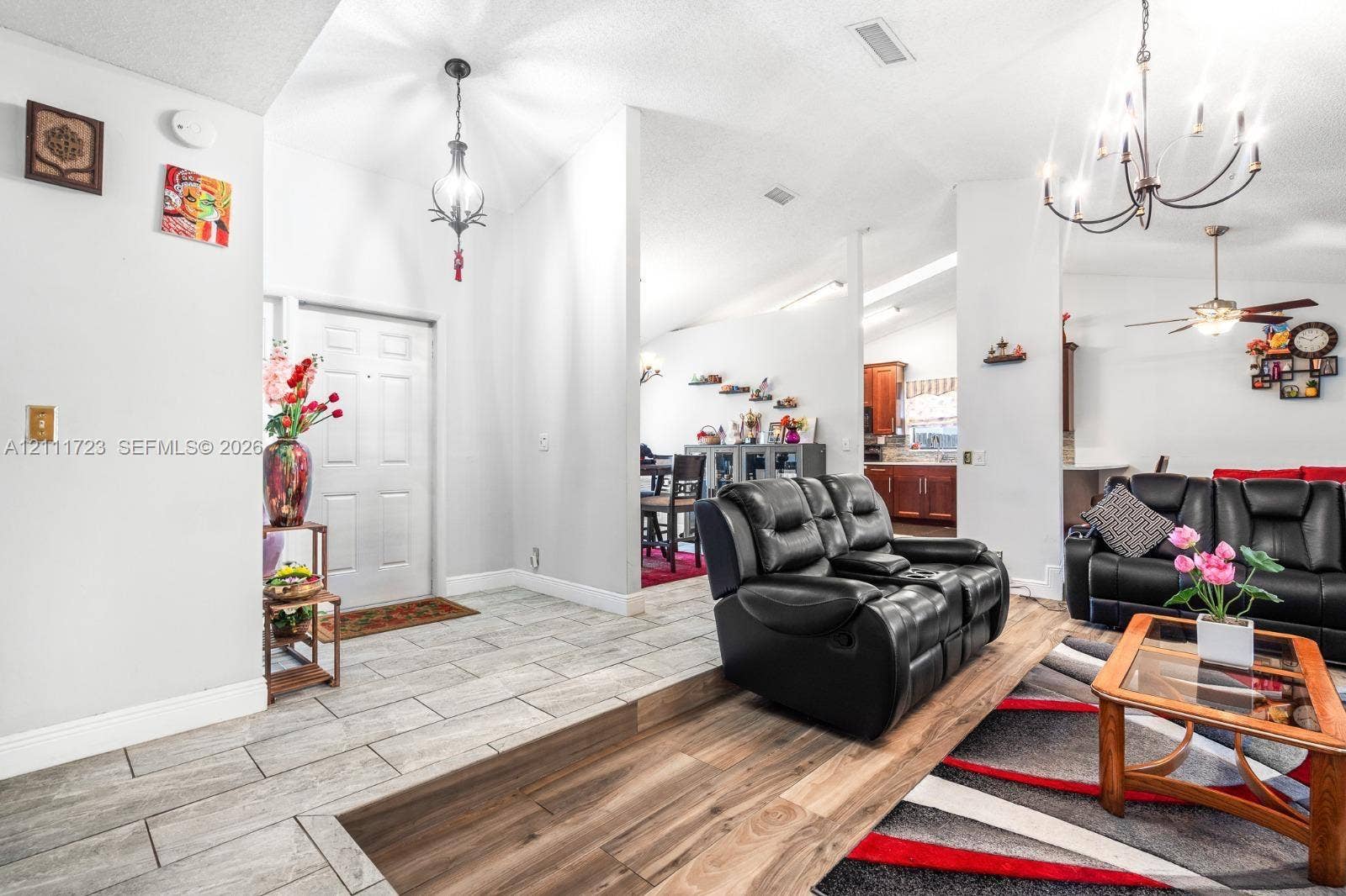 8541 NW 51st Court, Lauderhill, FL 33351 Open interior featuring vaulted ceilings, light-tone ceramic tile flooring, wood-finish flooring, and multi-arm chandelier lighting
