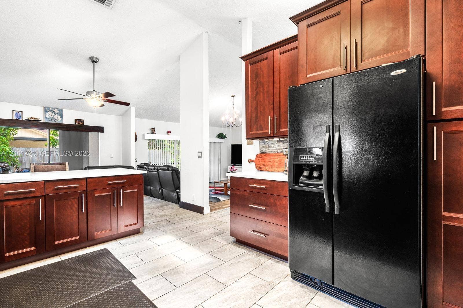 8541 NW 51st Court, Lauderhill, FL 33351 Kitchen featuring rich-toned wood cabinetry, stone-style countertops, large-format tile flooring, and a ceiling fan