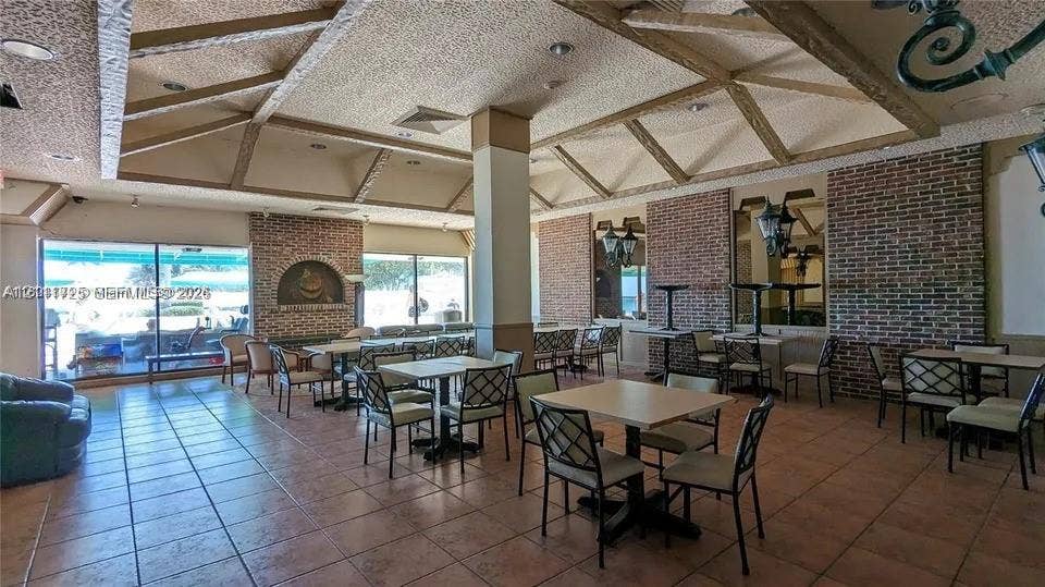 3725 S Ocean Drive, #508, Hollywood, Hollywood, FL 33019 Vaulted ceiling with exposed wood beams, red brick accent walls, ceramic tile flooring, and large sliding glass doors