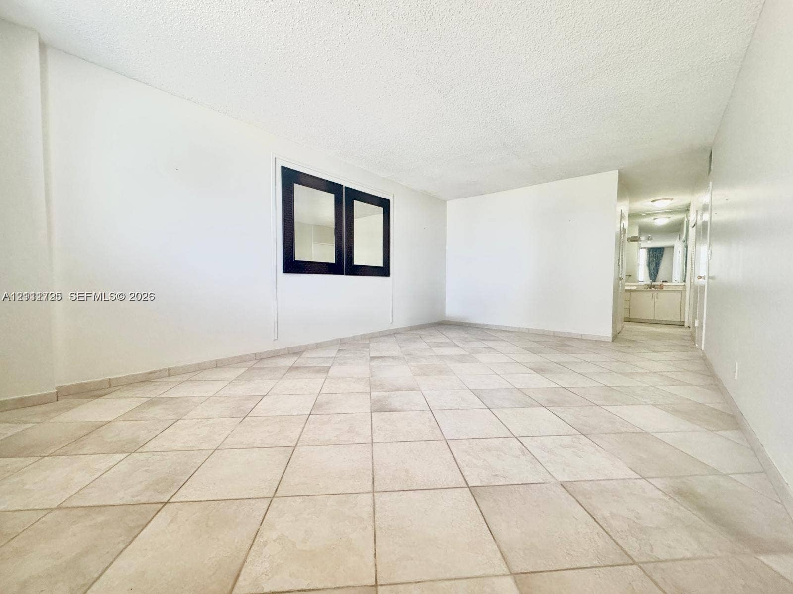 3725 S Ocean Drive, #508, Hollywood, Hollywood, FL 33019 Open-concept living space featuring large-format ceramic tile flooring, neutral walls, and a recessed black-framed wall mirror