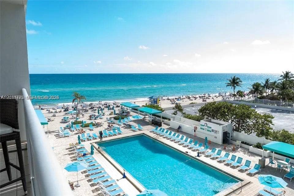 3725 S Ocean Drive, #508, Hollywood, Hollywood, FL 33019 Elevated balcony overlooking an expansive swimming pool, paved pool deck, sandy beach, and ocean shoreline