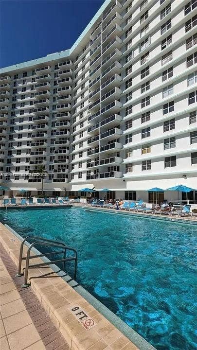 3725 S Ocean Drive, #508, Hollywood, Hollywood, FL 33019 In-ground swimming pool featuring a brick-paver deck and metal ladder access, situated at the base of a high-rise building with multiple private balconies