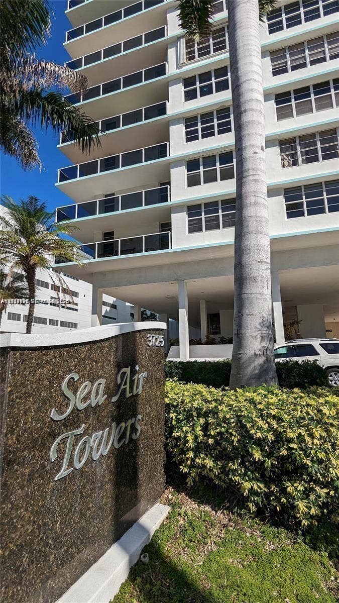 3725 S Ocean Drive, #508, Hollywood, Hollywood, FL 33019 High-rise exterior featuring stacked balconies with glass railings, polished stone monument signage, and mature landscaping