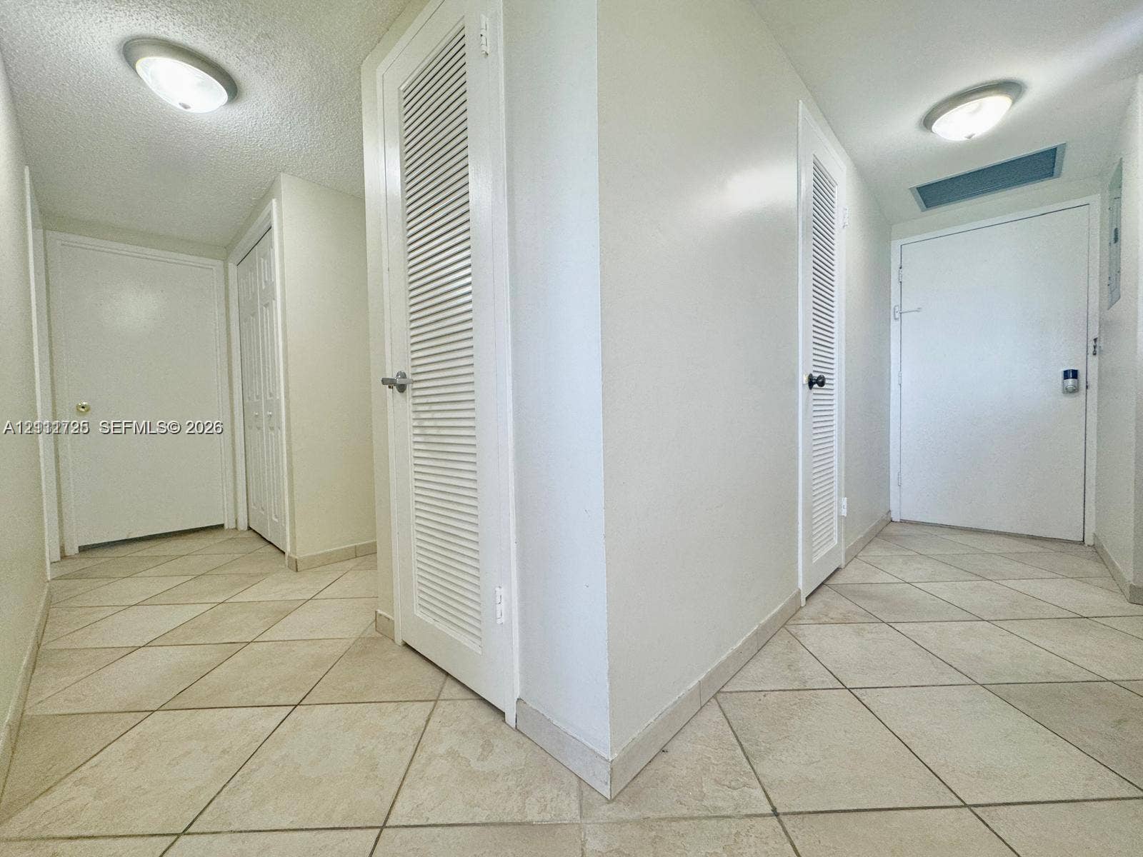 3725 S Ocean Drive, #508, Hollywood, Hollywood, FL 33019 Hallway featuring diagonal tile flooring, flush-mount ceiling lighting, and multiple louvered closet doors