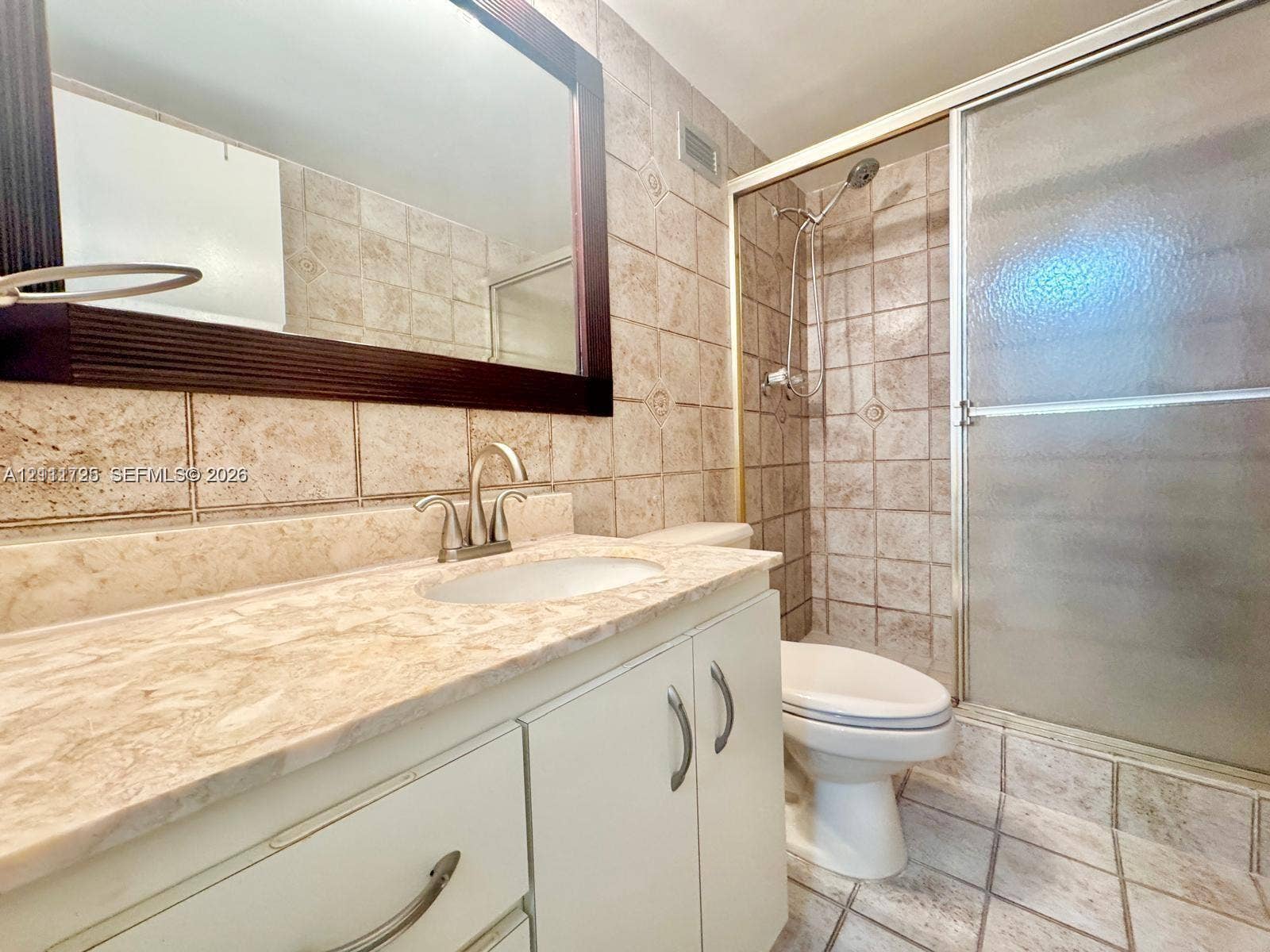 3725 S Ocean Drive, #508, Hollywood, Hollywood, FL 33019 Bathroom featuring a vanity with stone-finish countertop, undermount sink, metal hardware, framed mirror, and a walk-in shower enclosure with tile surround
