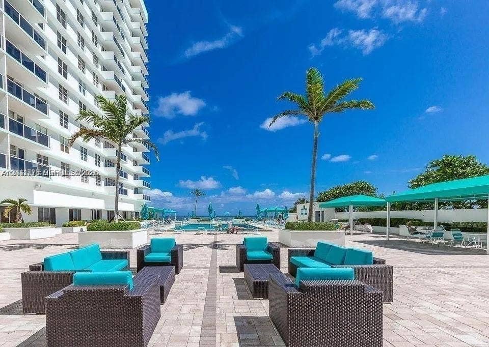 3725 S Ocean Drive, #508, Hollywood, Hollywood, FL 33019 Paved pool deck featuring an in-ground swimming pool, decorative palm trees, built-in concrete planters, and shaded outdoor structures
