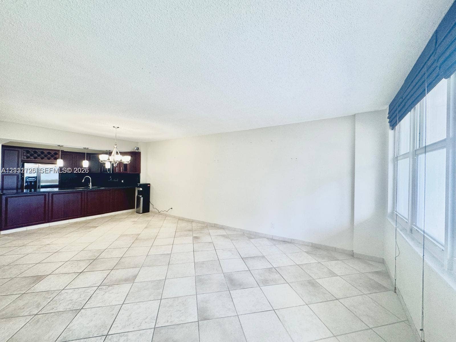 3725 S Ocean Drive, #508, Hollywood, Hollywood, FL 33019 Open-concept interior featuring large-format tile flooring, recessed ceiling lighting, and a kitchen with dark wood-finish cabinetry, a built-in wine rack, and a dark countertop