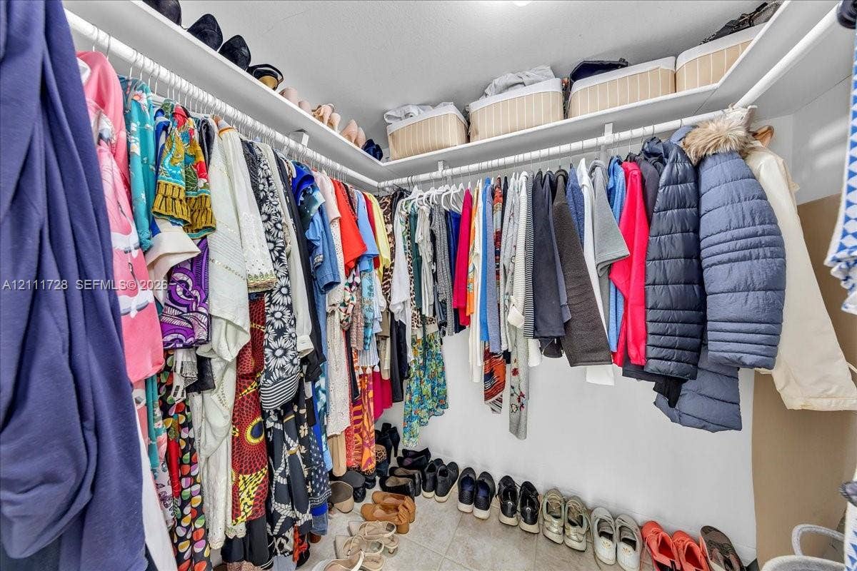 Walk-in closet featuring multi-level white wire shelving and tile flooring