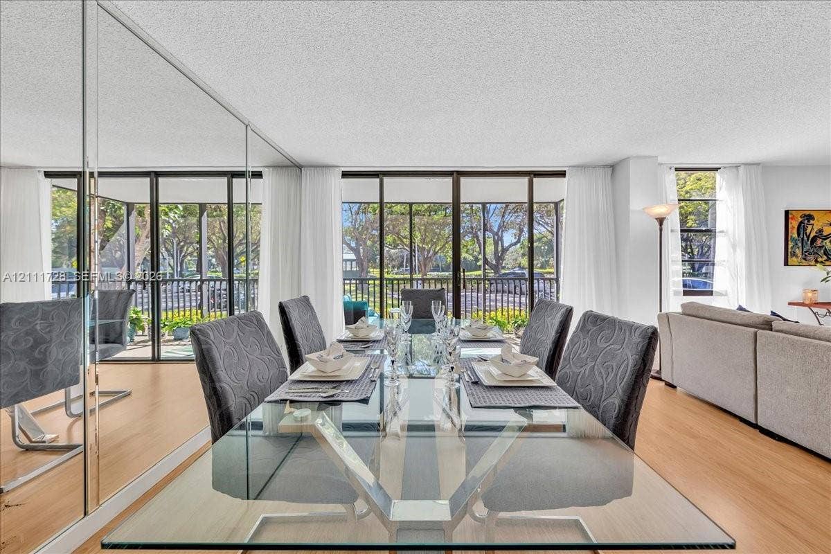Floor-to-ceiling mirrored wall, wood-finish flooring, and expansive glass sliding doors featuring screen enclosures