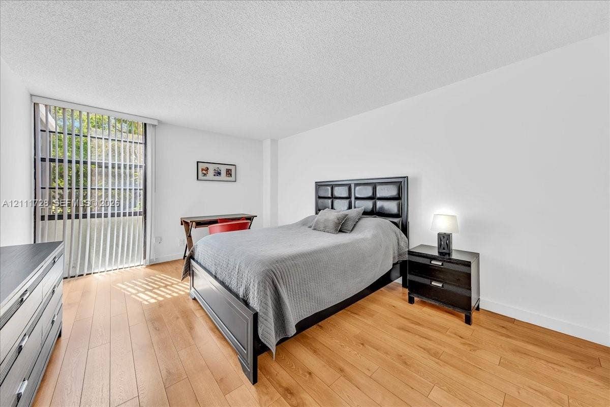 Wood-finish flooring, full-height floor-to-ceiling windows, and vertical window blinds