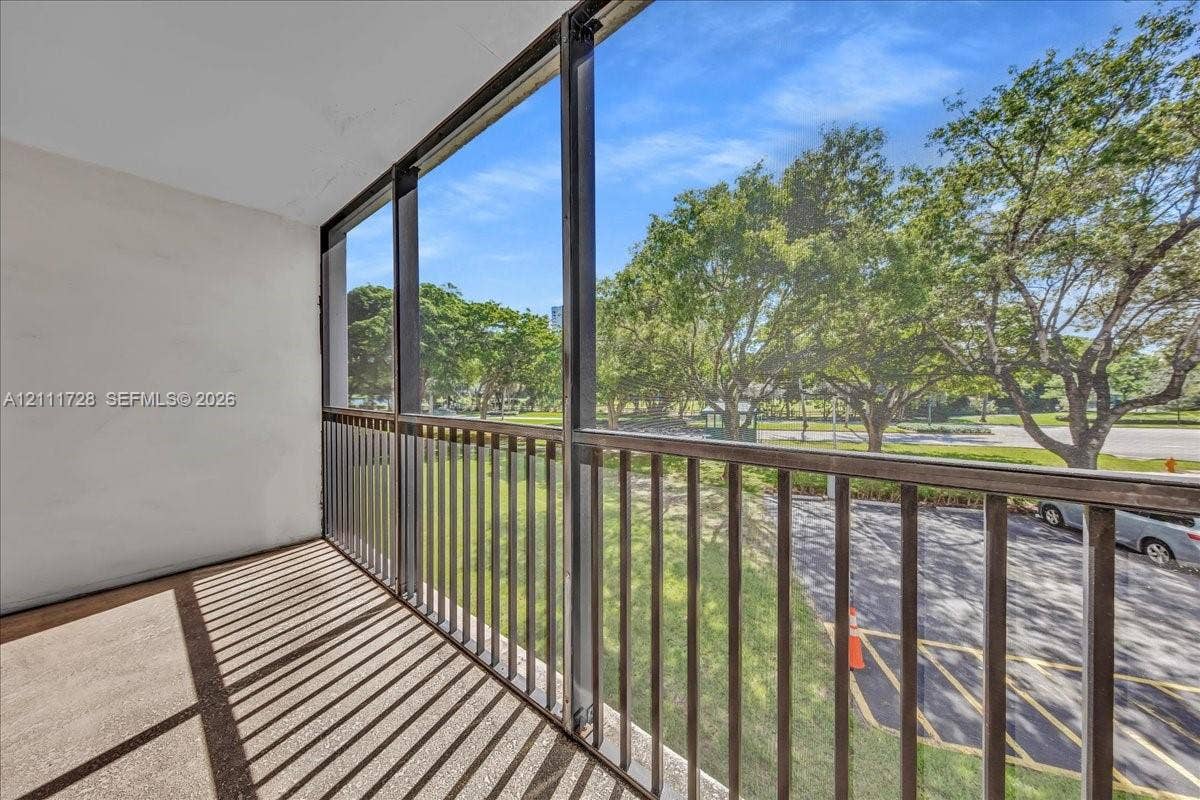 Screened-in balcony featuring concrete flooring, metal railing, and floor-to-ceiling insect screening