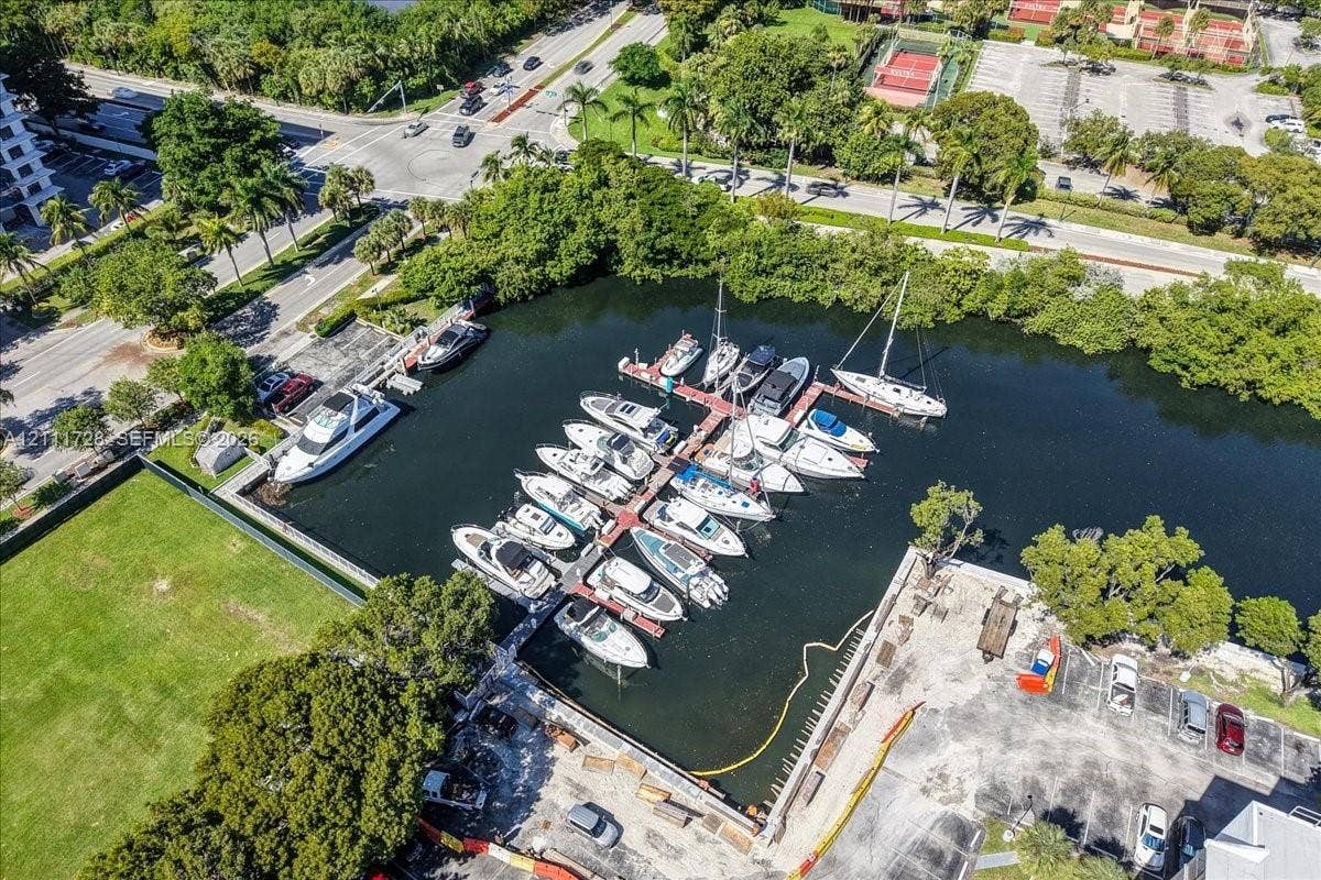 Aerial perspective featuring a private marina with multiple boat slips, deep-water access, a concrete bulkhead, and paved parking