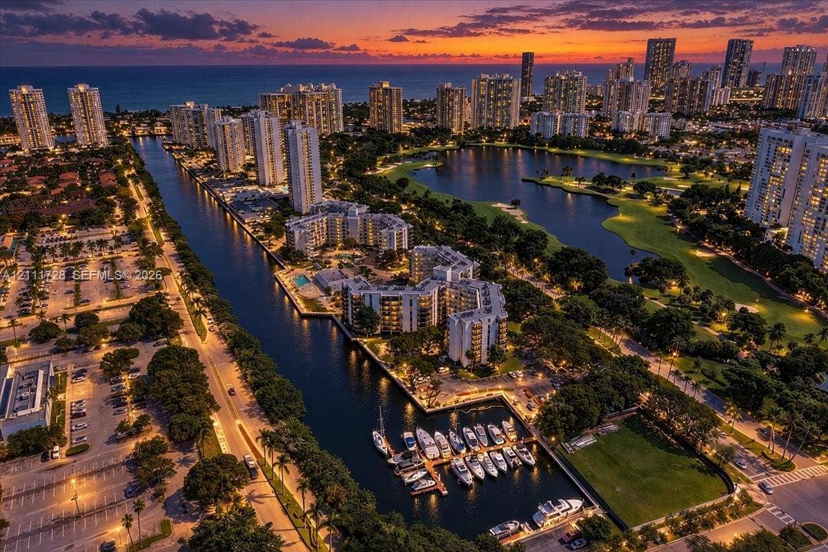 Aerial perspective of a coastal waterfront community featuring deep-water canal access, private boat slips, multi-level residential structures, and landscaped green space
