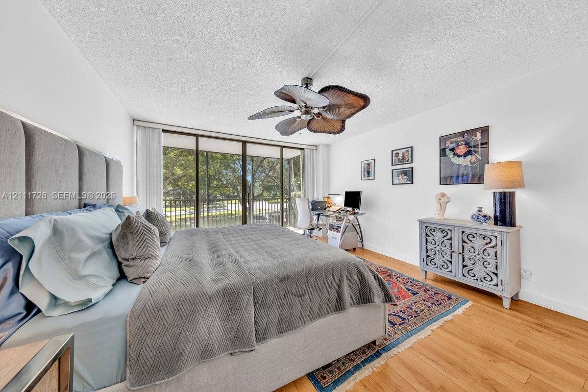 Wood-finish flooring, ceiling fan with palm-leaf style blades, and sliding glass doors with exterior access
