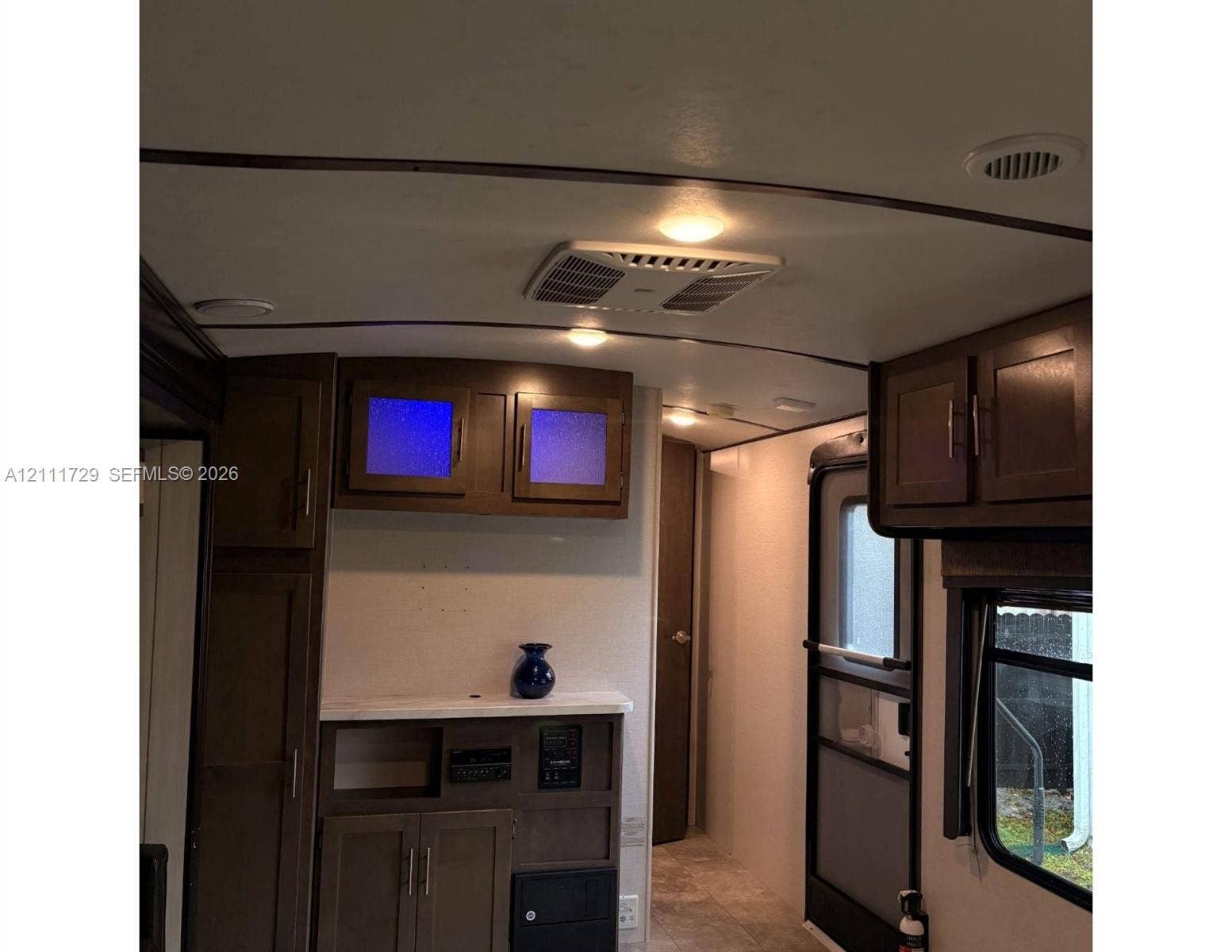 Dark wood-finish cabinetry featuring frosted glass door inserts, built-in lower console with stone-finish countertop, and recessed ceiling lighting