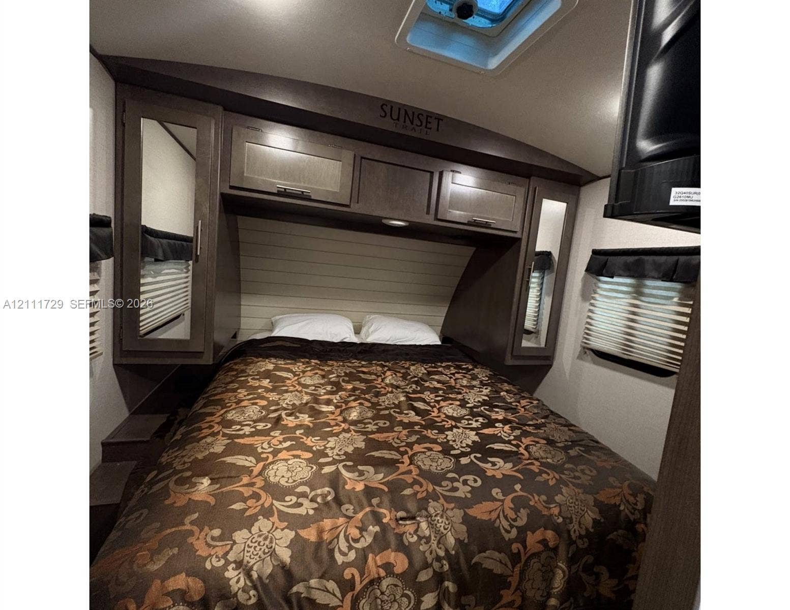 Built-in cabinetry with integrated mirrored wardrobes, overhead skylight, and pleated window shades